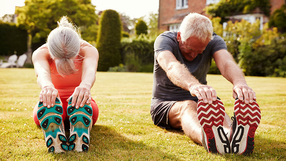 Two seniors stretching in the grass