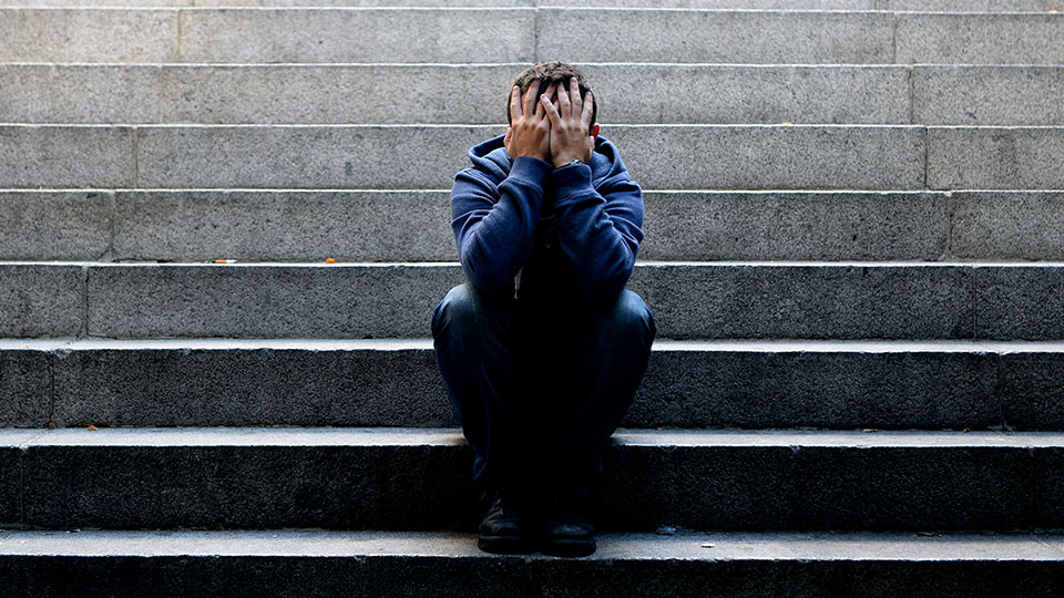 Young man suffering depression sitting on ground street concrete stairs